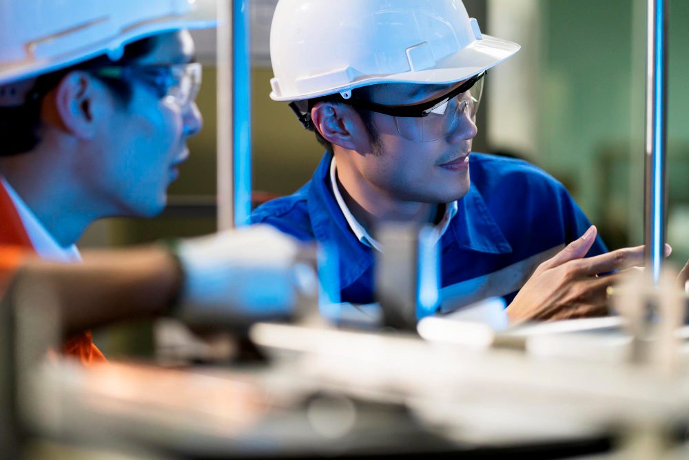 Engineers in safety helmets discussing factory equipment