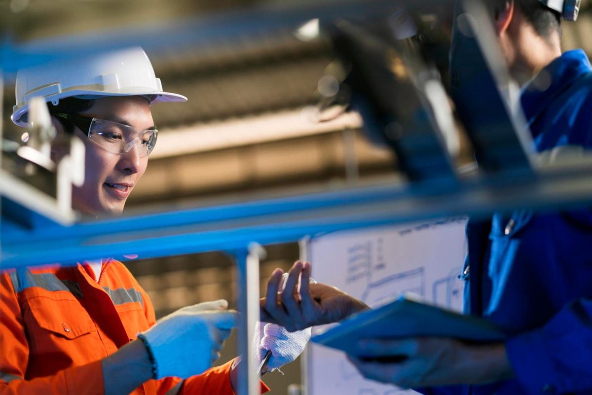 Factory workers discussing equipment beside a laptop