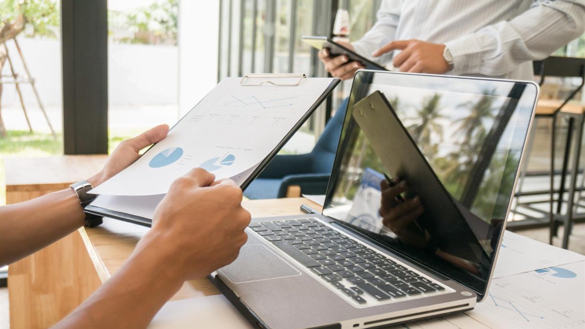 People reviewing documents and devices around a table