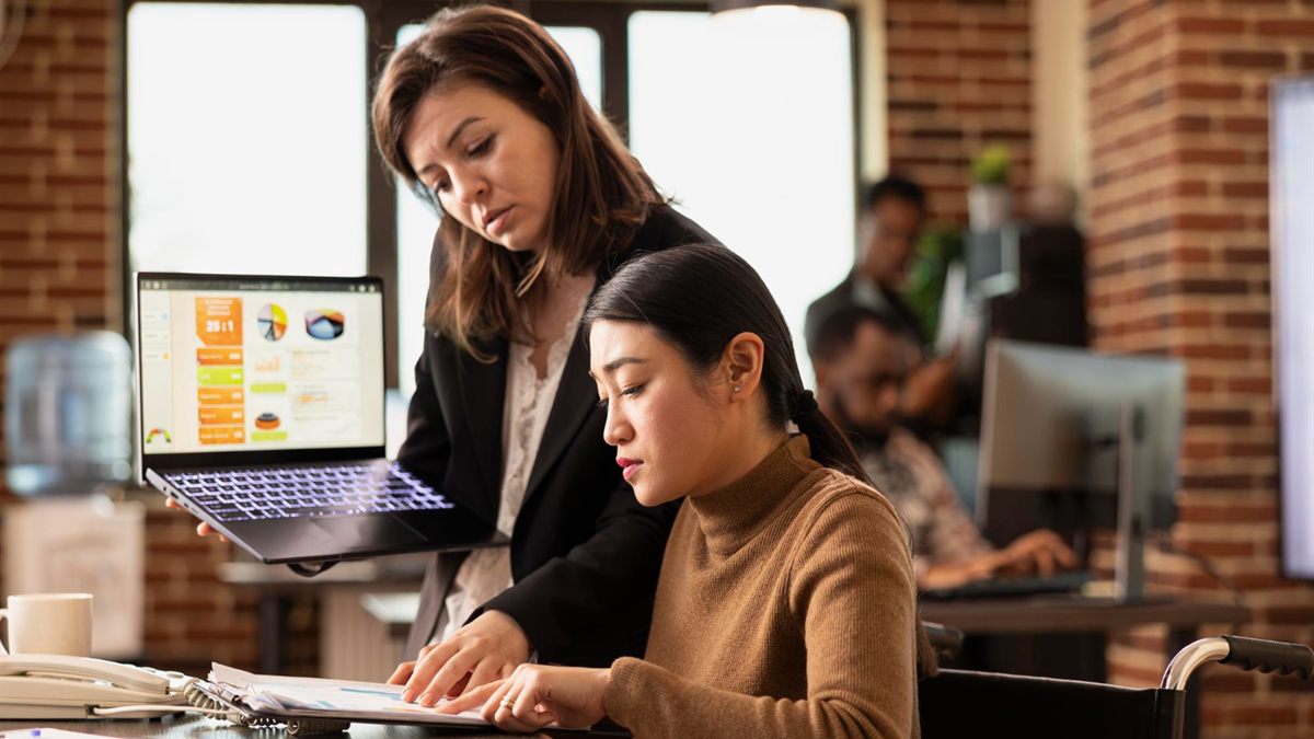 Colleagues reviewing a laptop and printed documents