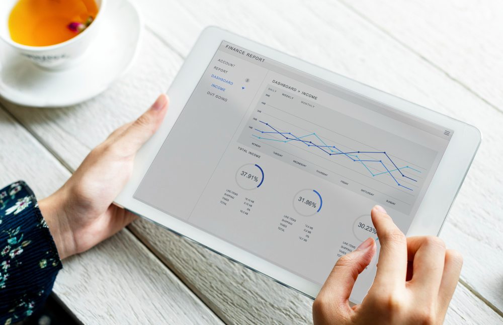 Hands holding a tablet displaying analytics charts