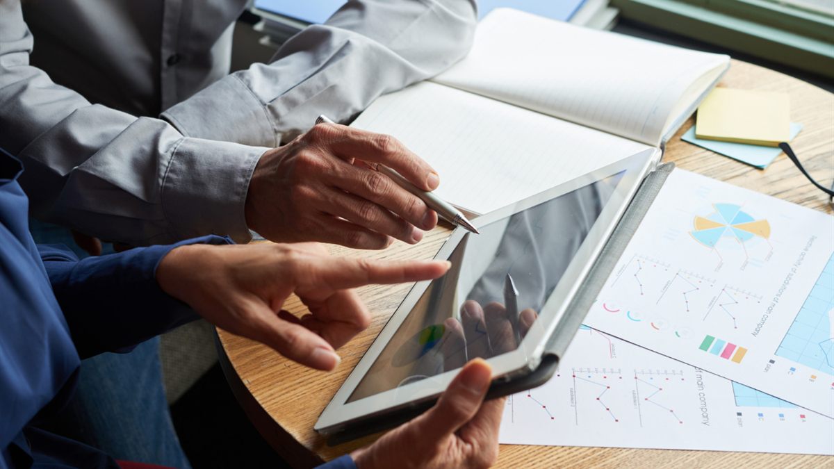 People reviewing a tablet and printed charts at a desk