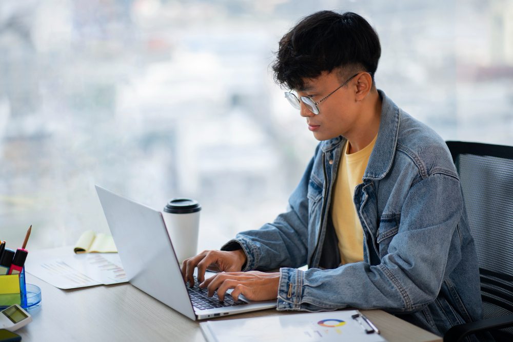 Student working on a laptop beside study materials