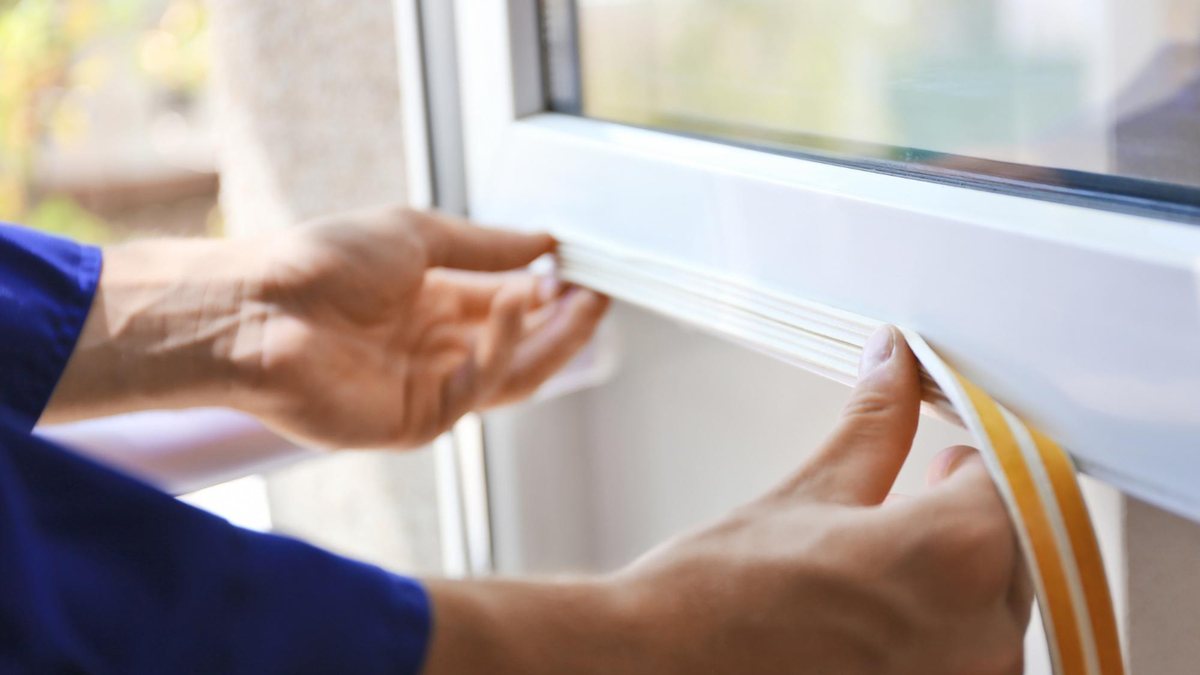 Hands fitting a sealing strip along a window frame